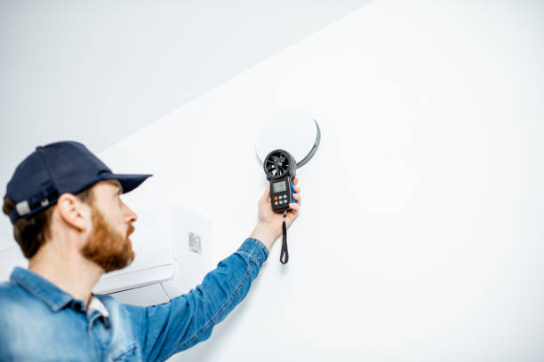 Handyman checking the speed of air ventilation with measuring tool on the white wall background